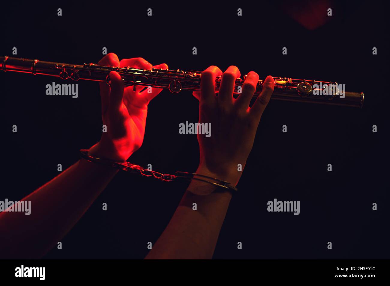 Mains d'une femme musicienne avec une flûte à main menottée sur fond noir de studio.Problèmes de jouer à des concerts, le concept de non-f Banque D'Images