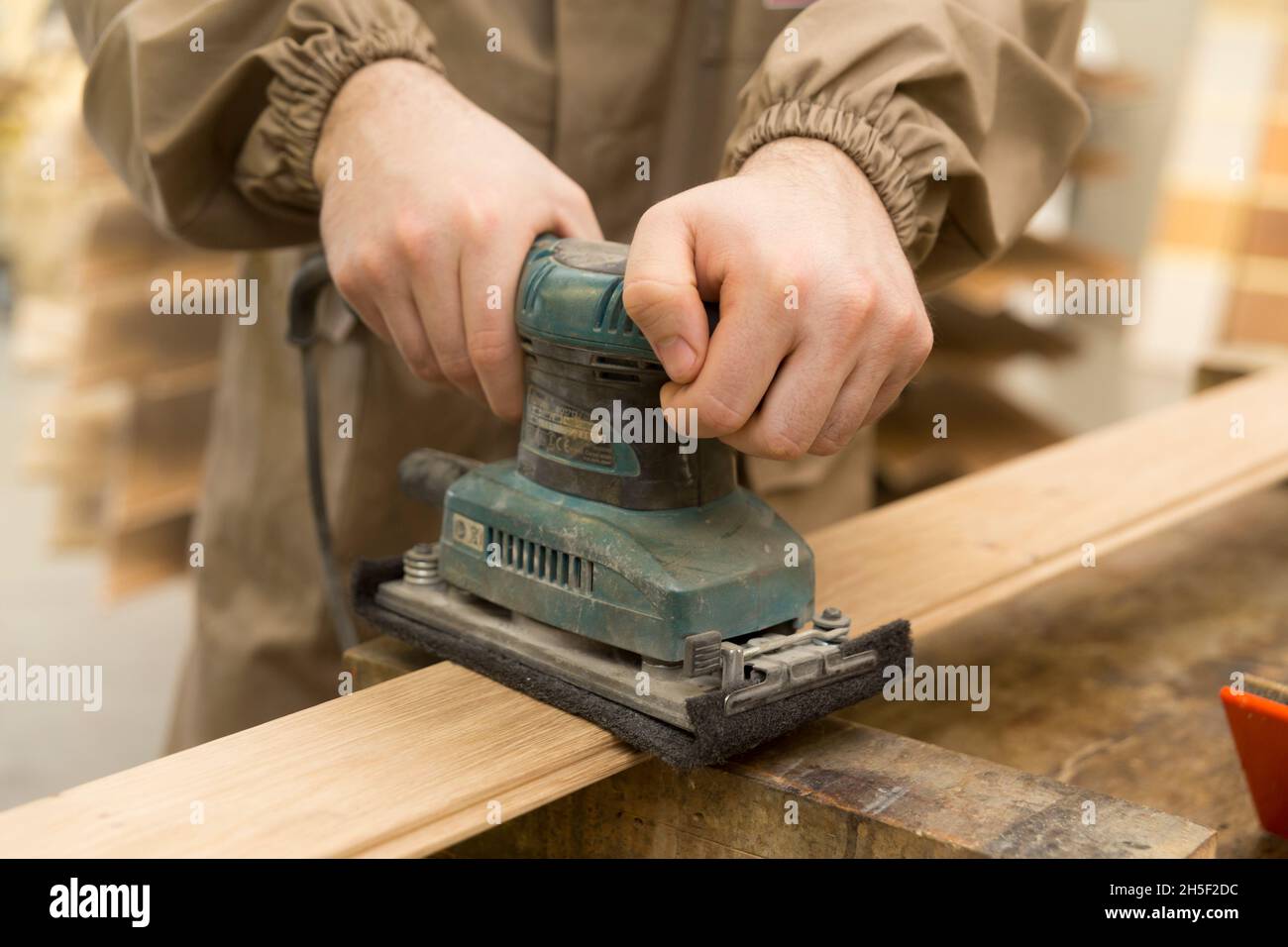 gros plan de la main du menuisier à l'aide d'une meuleuse sur une surface en bois Banque D'Images