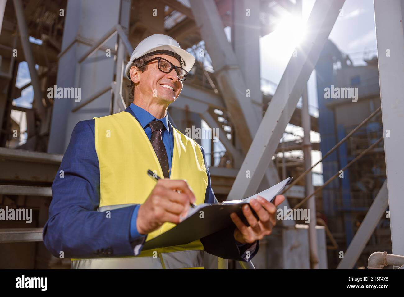 Un homme enjoué écrit des documents à l'extérieur à l'usine Banque D'Images