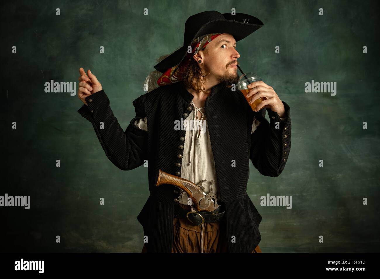 Portrait d'un homme brutal, pirate médéival avec jus d'orange au pistolet isolé sur fond sombre. Banque D'Images