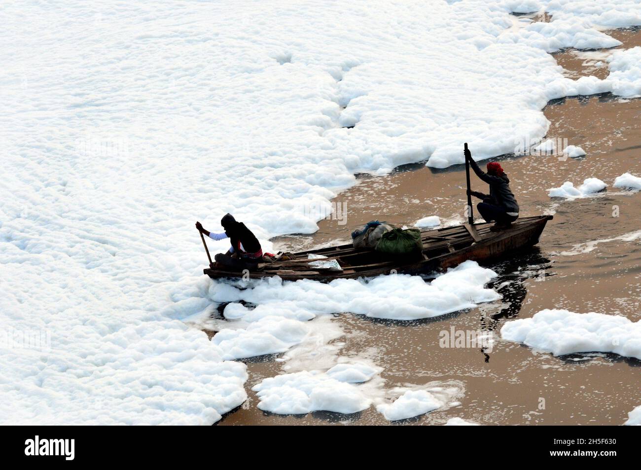 Non exclusif: NEW DELHI, INDE - 9 NOVEMBRE 2021: Un pêcheur voyage dans un bateau, essayant de traverser une épaisse couche de mousse toxique qui flotte dessus Banque D'Images