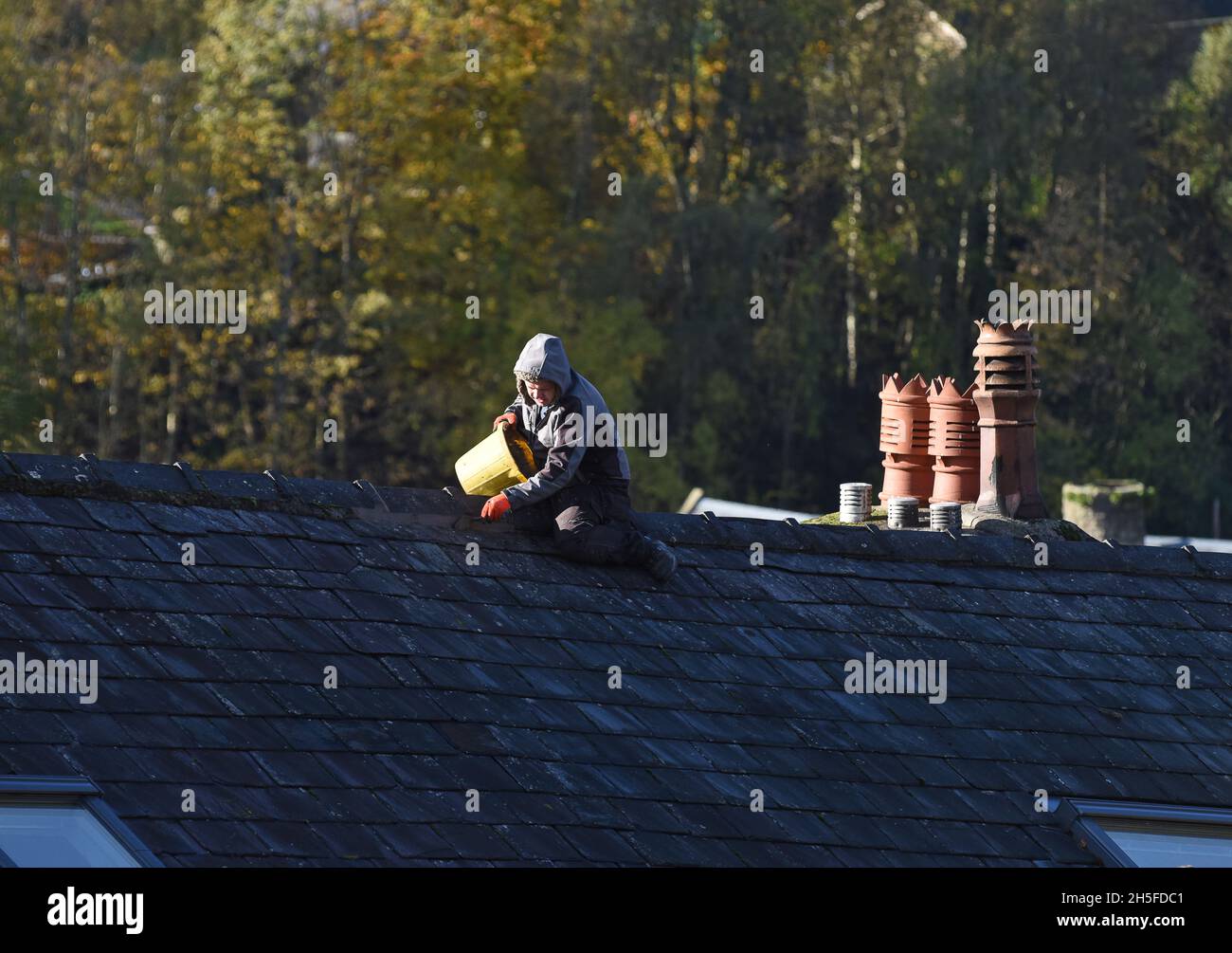 Constructeur homme répare le toit sur la maison sans équipement de santé et de sécurité Grande-Bretagne, Royaume-Uni Banque D'Images