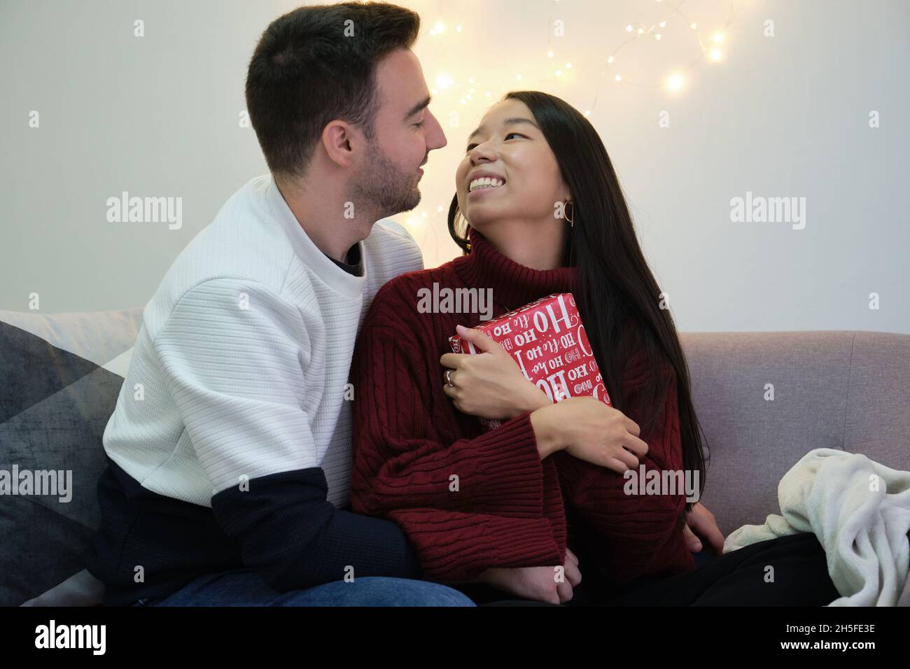Couple romantique et multiracial échangeant des cadeaux de Noël. Banque D'Images