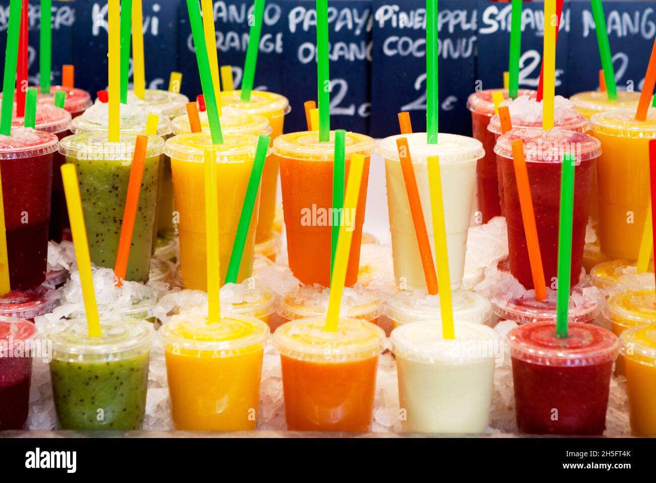 Les smoothies Obst (papaye, Kiwi, Erdbeere, Mango, Orange) abgefüllt en transparent Plastikbechern mit bunten Strohhalmen.Auf einem Markt à Barcelone. Banque D'Images