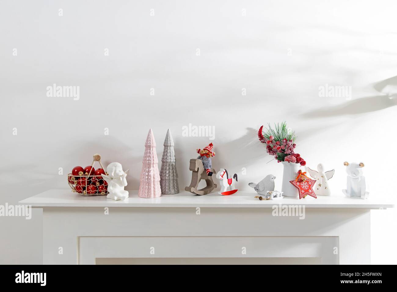 Décoration de l'intérieur de l'appartement pour Noël.Une guirlande de figurines en bois sculpté.Bougies et figurines en céramique sur une fausse cheminée.Copie s Banque D'Images