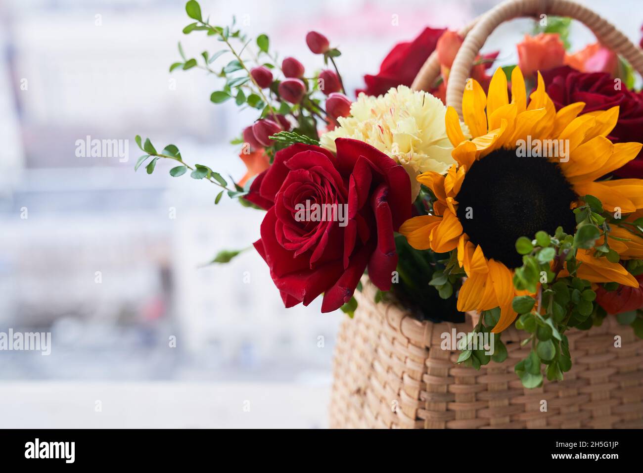 Gros plan d'un panier avec de belles fleurs d'automne faites de roses rouges, de tournesol et de feuilles vertes. Le concept des vacances. Copier l'espace. Photo de haute qualité Banque D'Images