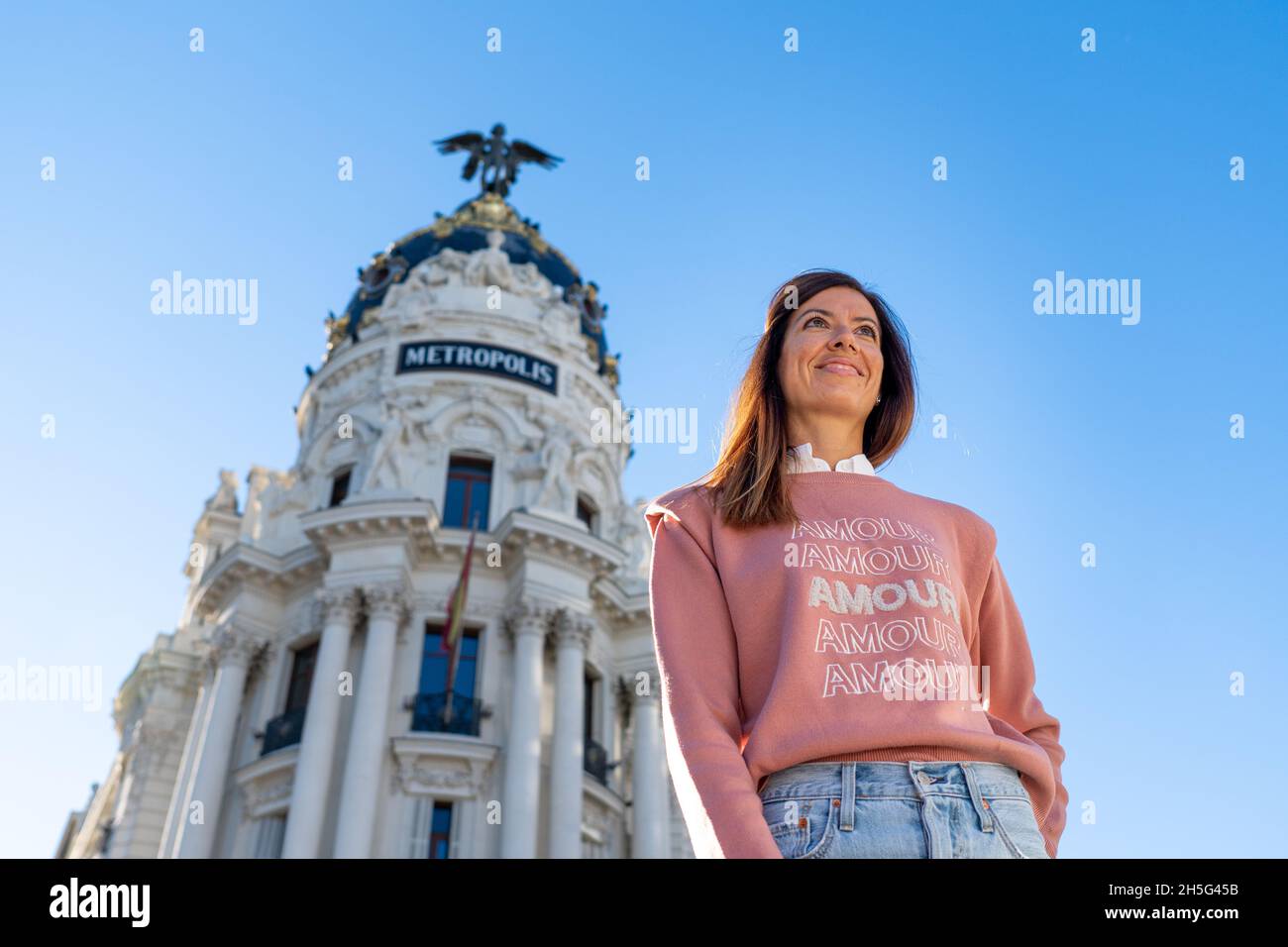 Femme en chandail rose et jeans posant dans le bâtiment Metropolis sur Gran via à Madrid Banque D'Images