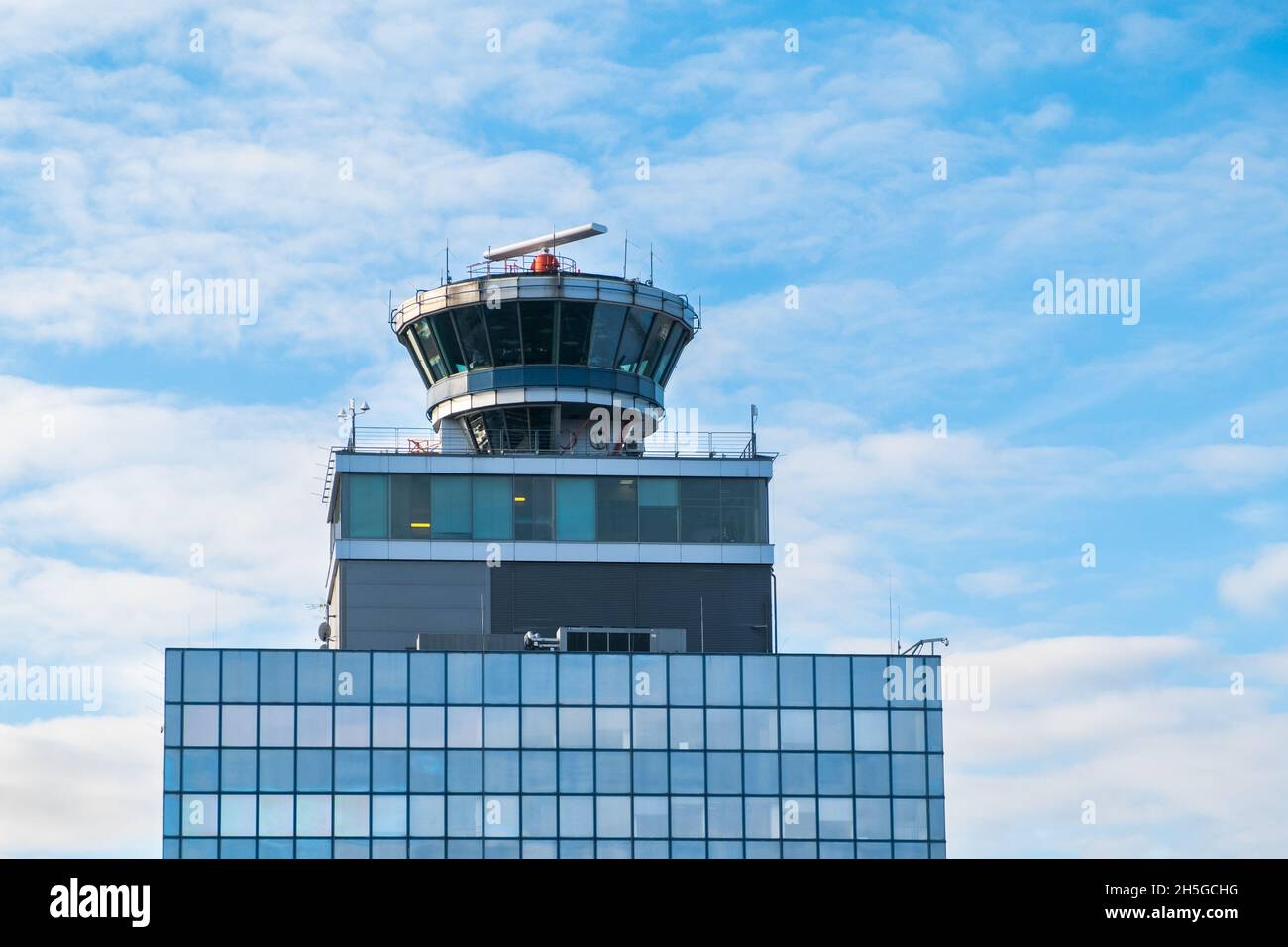 Tour de contrôle d'aéroport avec cabine transparente.Poste de commande du transport aérien sur le dessus du bâtiment à plusieurs étages, ciel bleu ciel lumière nuages arrière-plan Banque D'Images