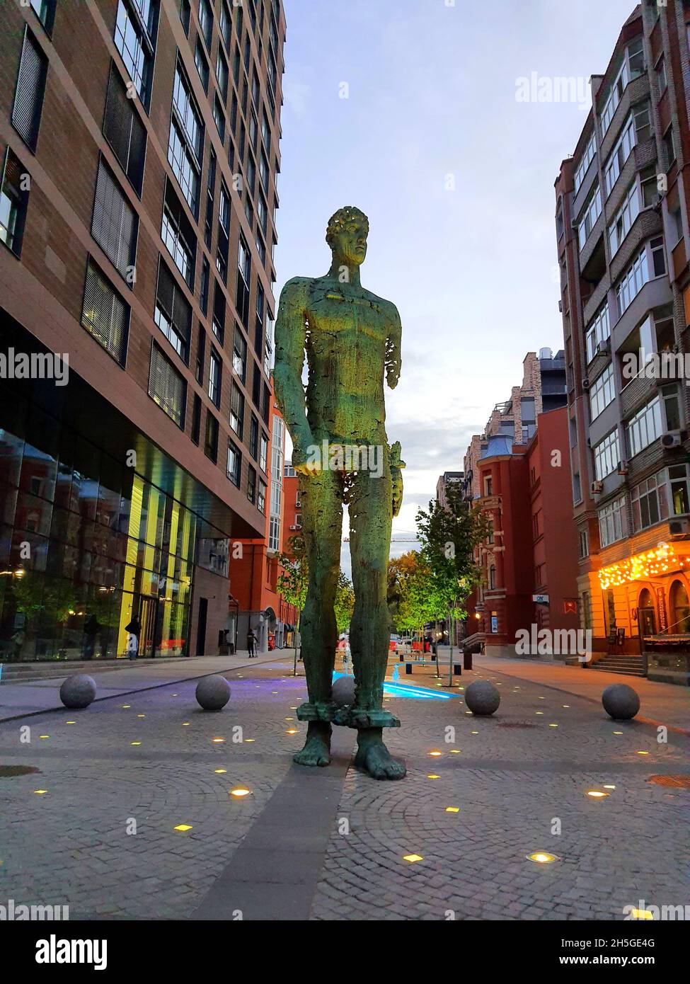 Une sculpture en fer forgé Atlant homme se dresse sur la rue parmi les gratte-ciel, de grands bâtiments.Objet d'art décoratif statue en métal dans la ville ukrainienne Dnipro Banque D'Images