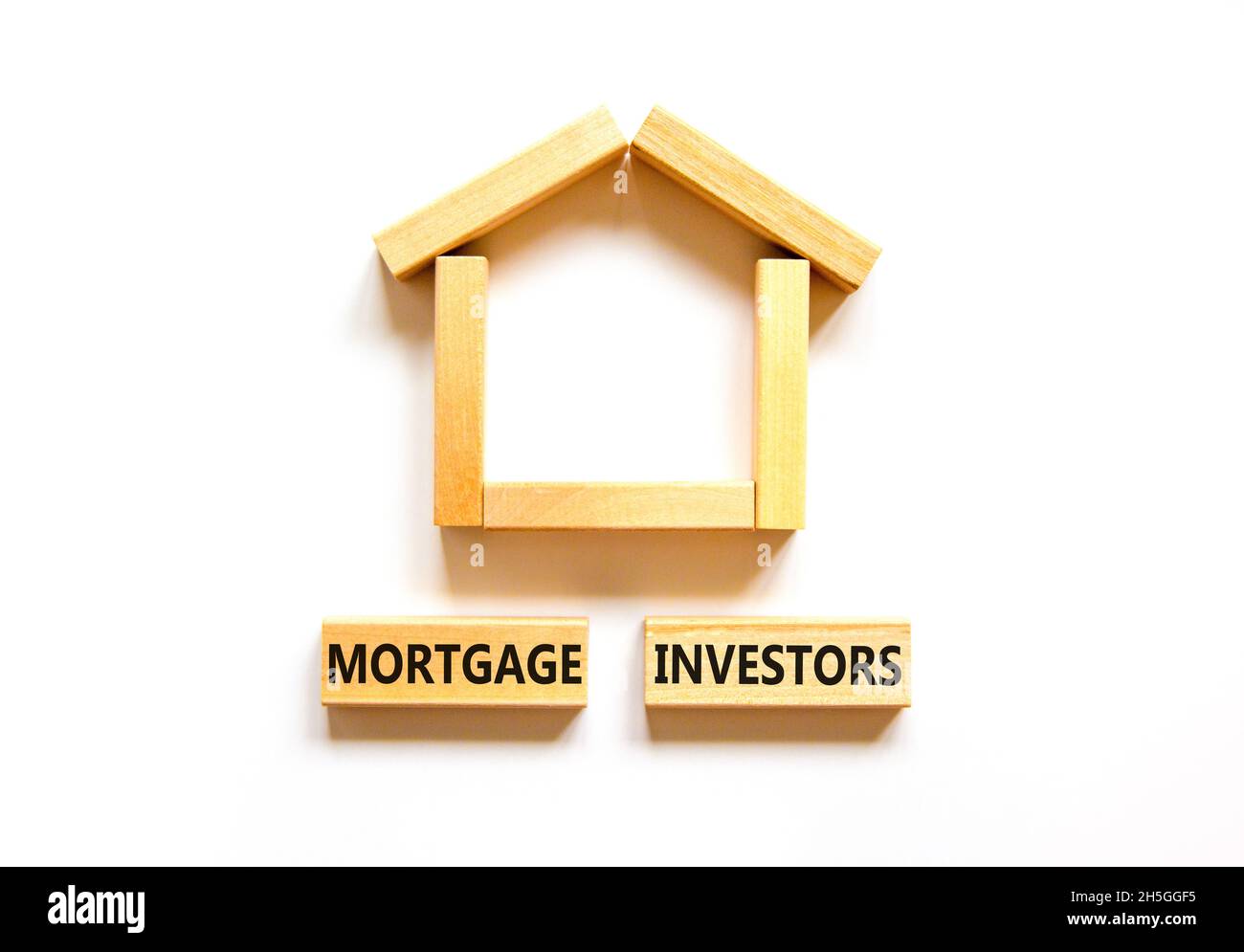 Symbole des investisseurs hypothécaires.Mots-clés 'Mortgage Investors' sur des blocs de bois près de la maison en bois miniature.Magnifique fond blanc.Affaires, mort Banque D'Images