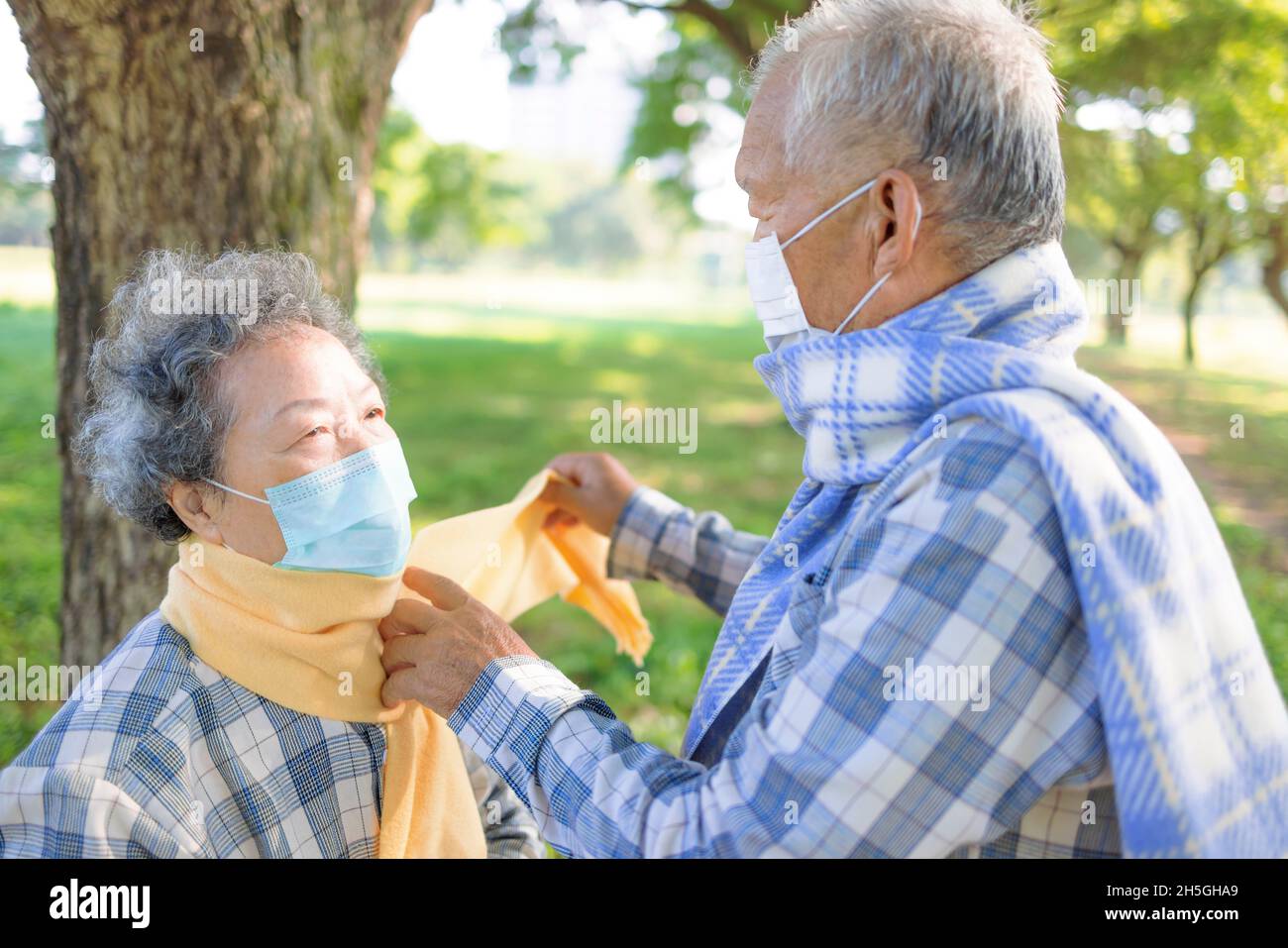 Un couple asiatique senior s'aide mutuellement à porter un tissu d'hiver chaud Banque D'Images
