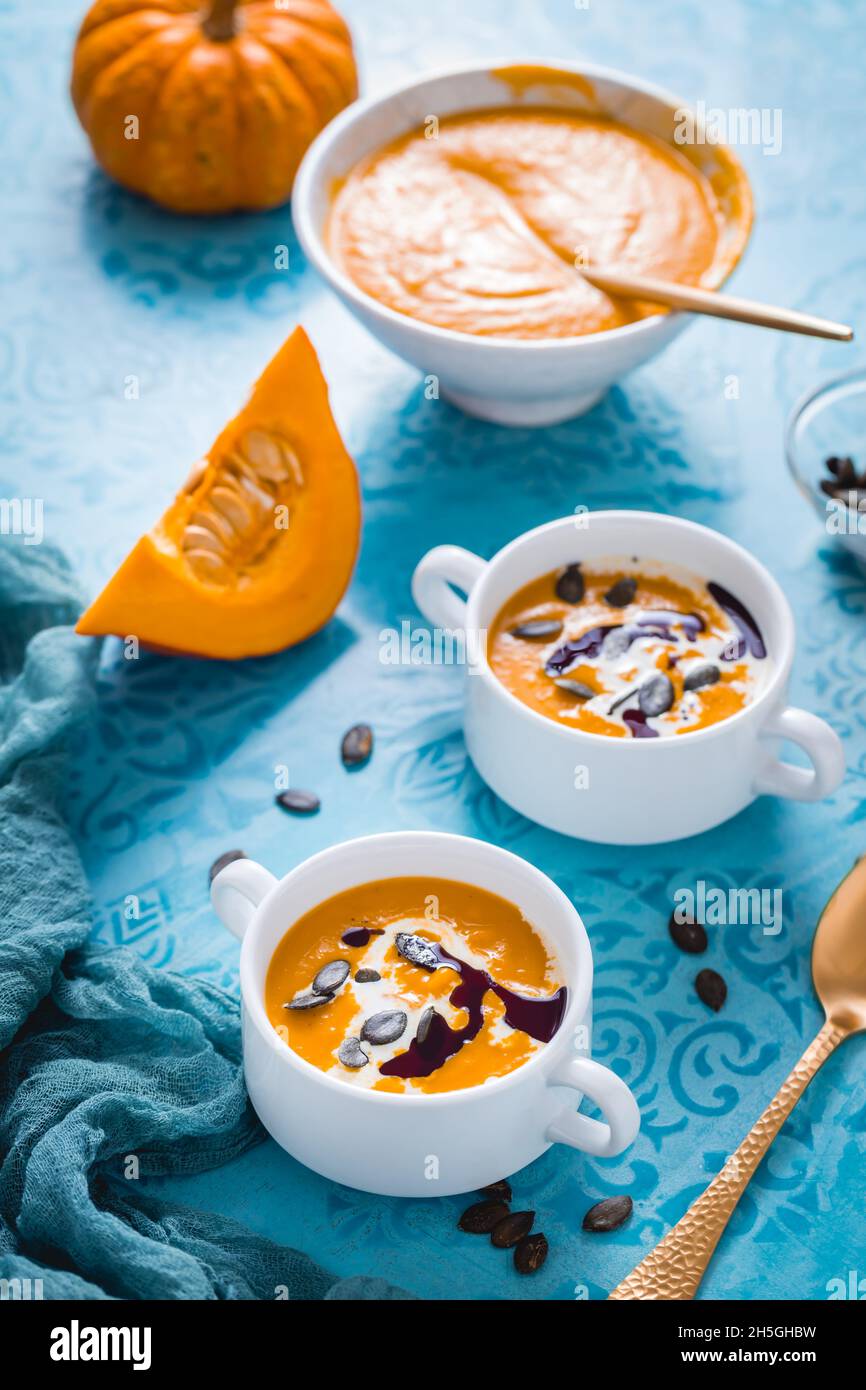 Soupe de potiron maison avec lait de coco, huile de potiron et graines sur fond bleu Banque D'Images