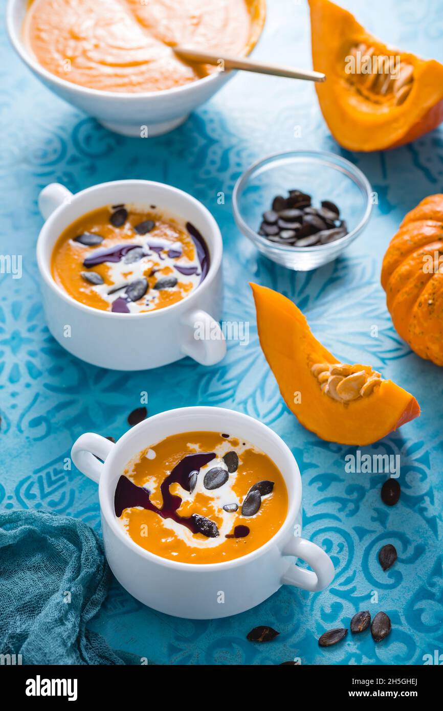 Soupe de potiron maison avec lait de coco, huile de potiron et graines sur fond bleu Banque D'Images
