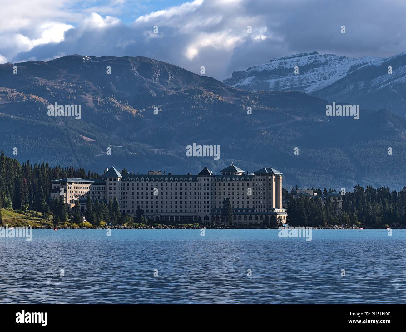 Vue sur le lac Louise le matin avec un hôtel célèbre sur la rive, devant les montagnes Rocheuses escarpées enneigées du parc national Banff, Canada. Banque D'Images