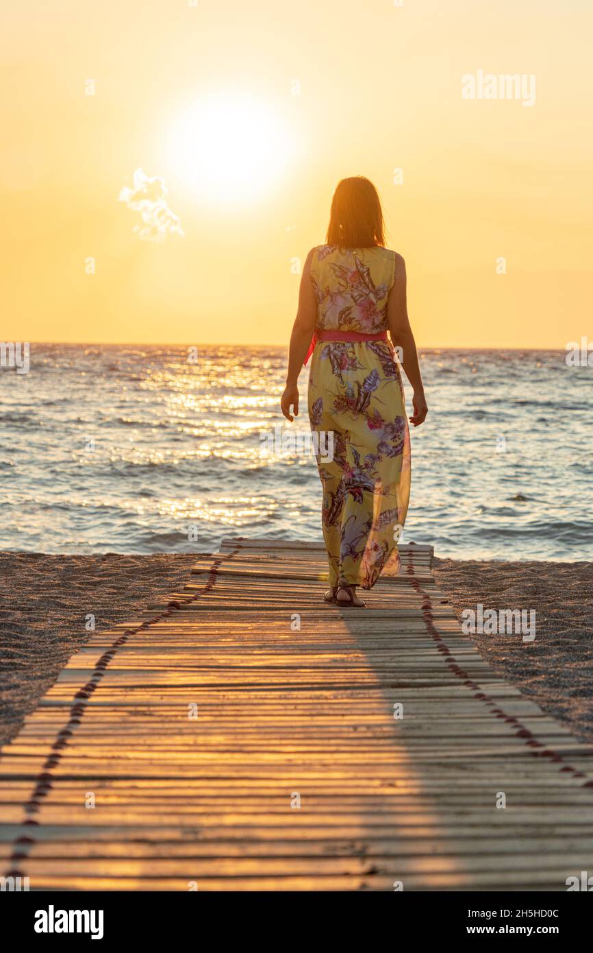 Belle femme avec robe contemplant la mer au coucher du soleil, Matala, Crète, Grèce Banque D'Images