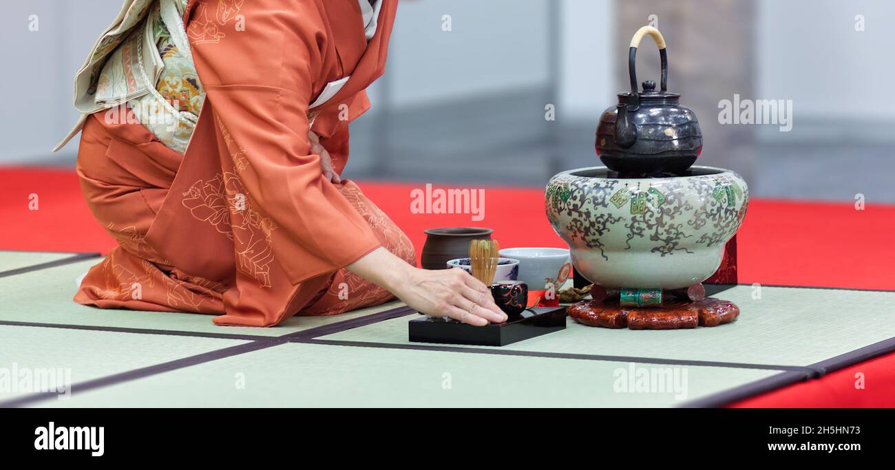 Une femme dans un kimono s'agenouillant sur un tatami prépare le thé lors d'une démonstration d'une cérémonie traditionnelle du thé japonais.L'image de gros plan. Banque D'Images