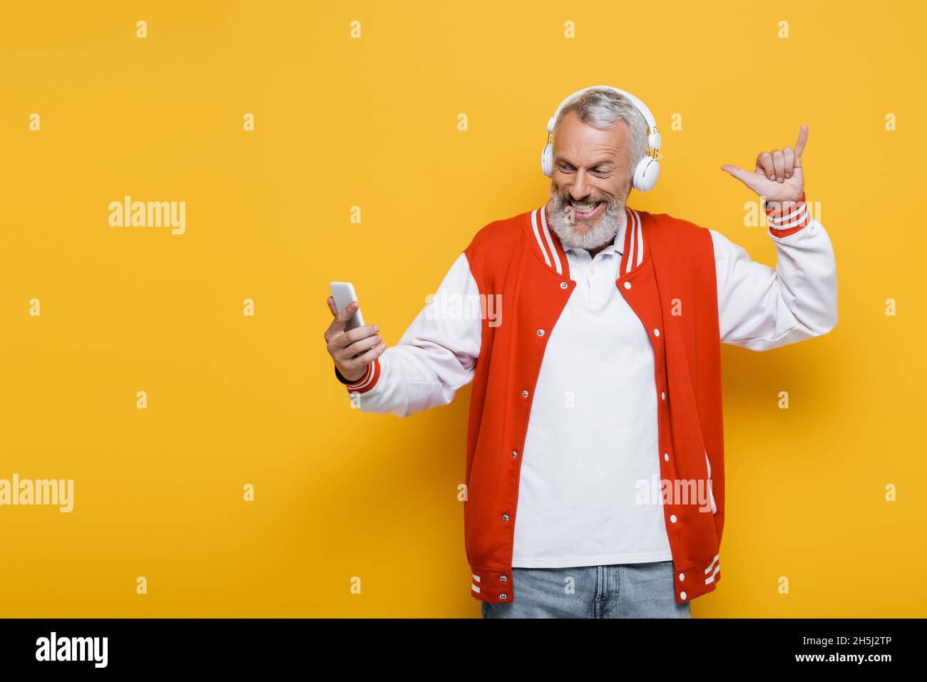 homme d'âge moyen positif dans un casque prenant le selfie tout en montrant pendre geste lâche sur jaune Banque D'Images