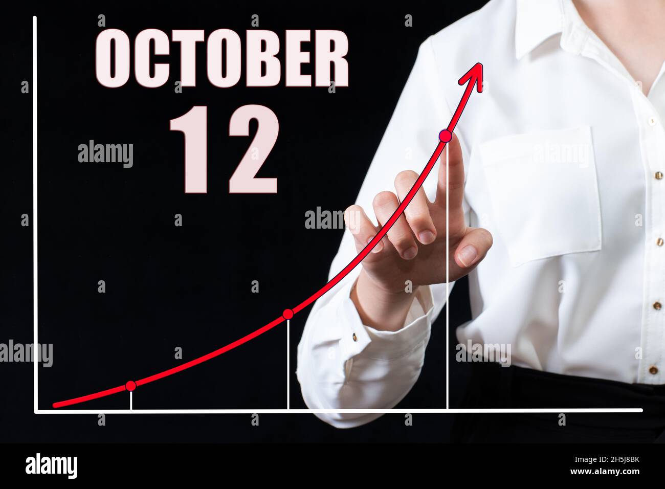 12e jour d'octobre.Main de femme d'affaires pointant vers le graphique et un calendrier avec la date du 12 octobre.Objectifs commerciaux pour la journée.Mois d'automne, Banque D'Images