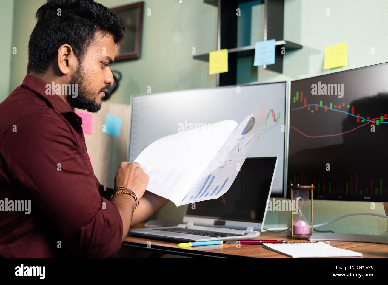 Trader analysant les données du marché boursier à partir de documents en regardant le moniteur - concprès de la planification de l'investissement, de la fabrication de l'argent et de la lecture de rapport financier. Banque D'Images