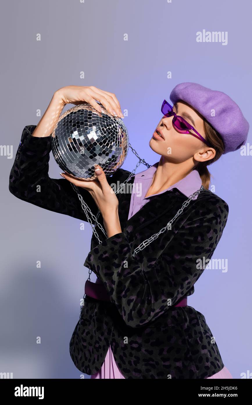 femme élégante en béret, lunettes de soleil et blazer avec imprimé animal  regardant le bal disco sur violet Photo Stock - Alamy