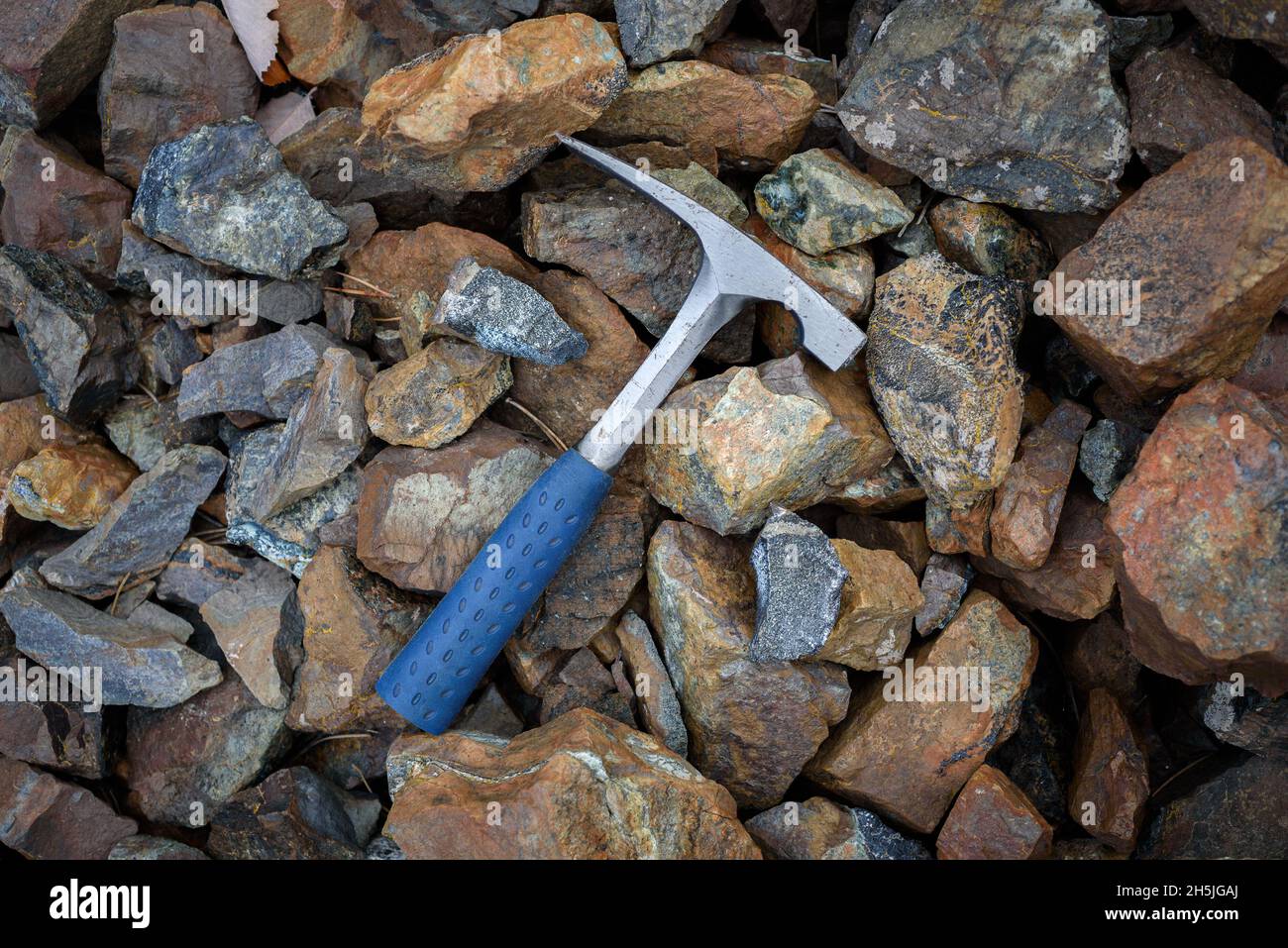 Pic de roche à bord biseauté, outil d'exploration géologue sur les roches naturelles fond dans la mine abandonnée de chromite à Chypre Banque D'Images