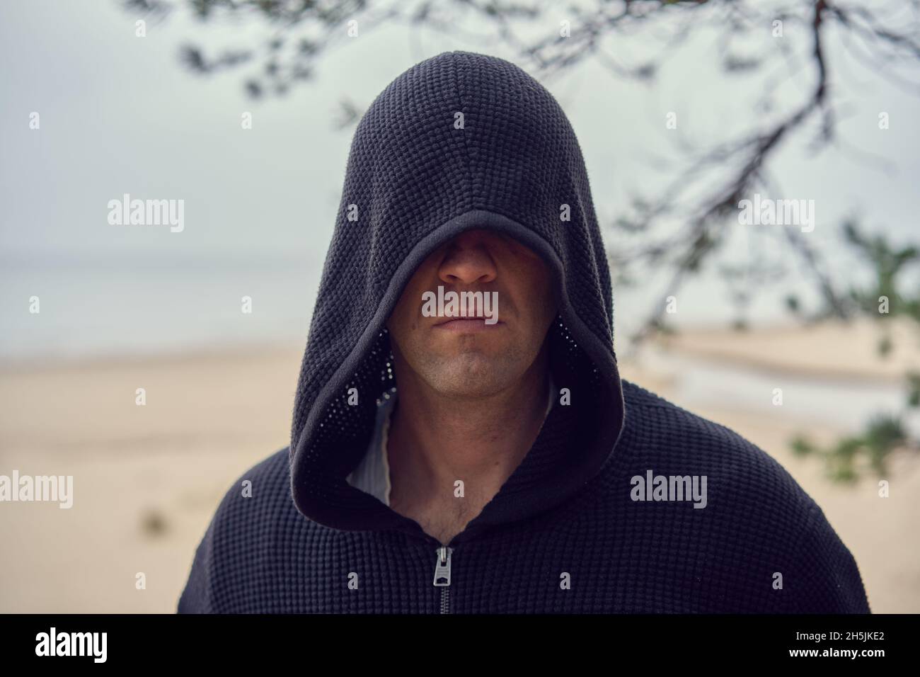 Une personne dans un sweat à capuche noir ressemble à un assassin.Cosplay.Chaussures de mer à l'arrière-plan.Photo de haute qualité Banque D'Images