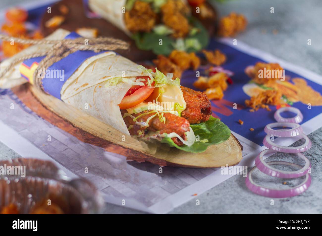 Rouleau de semeskh de poulet frais avec tomates fraîches, salade, fromage et oignons isolés sur fond bleu vif.Mise au point du côté view.selective Banque D'Images