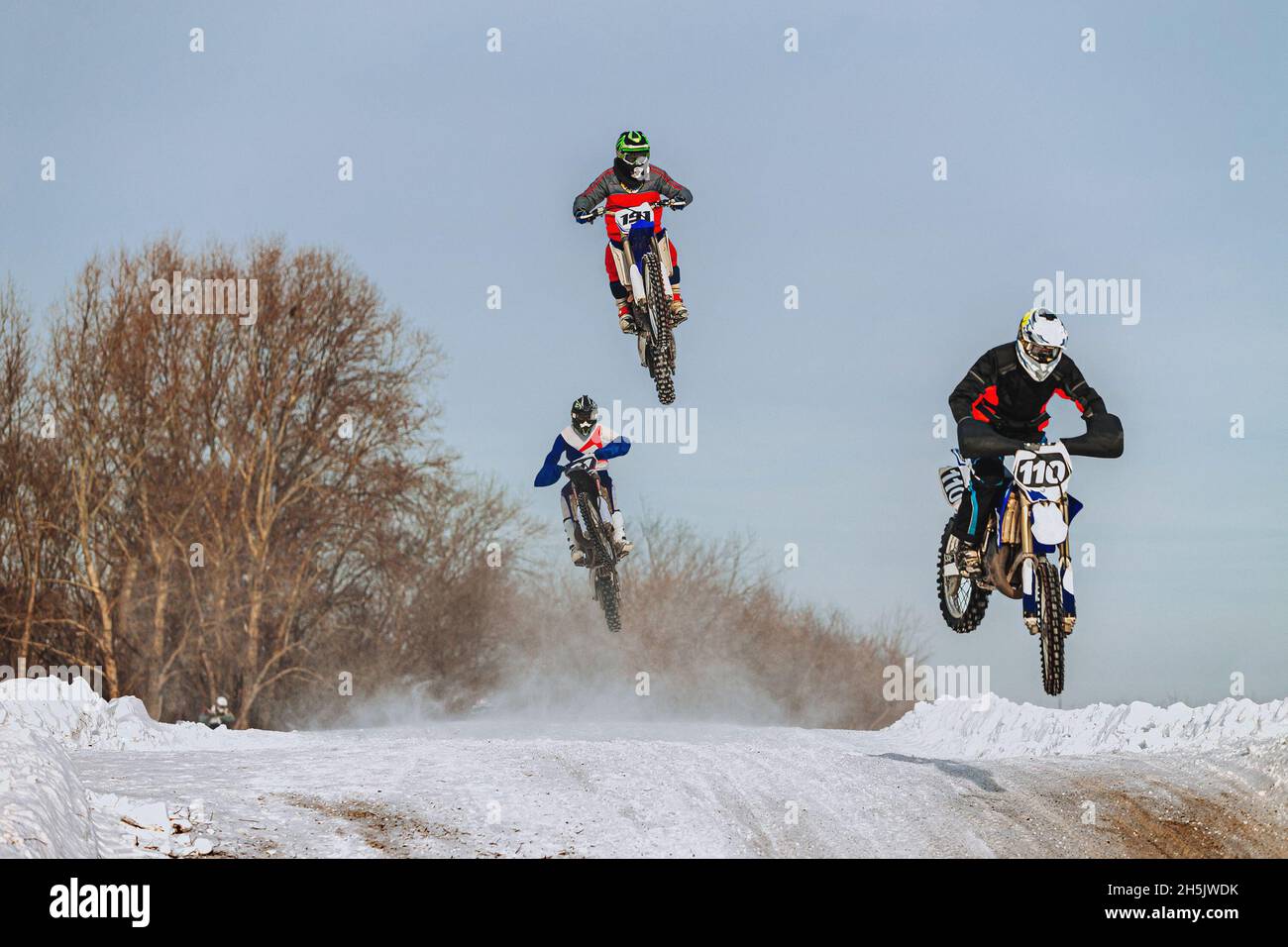 groupe de motocyclistes sautent sur la colline en motocross d'hiver Banque D'Images