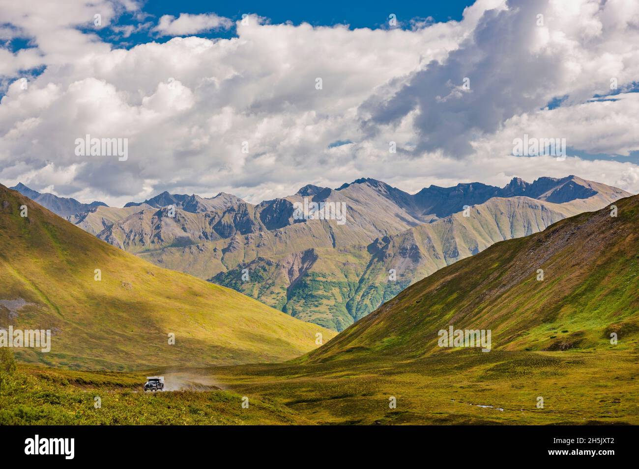 Un camion monte sur la route jusqu'au Hatcher Pass Lodge et à la mine d'or de la monnaie, avec la toundra de couleur automnale et les monts Talkeetna en arrière-plan,... Banque D'Images