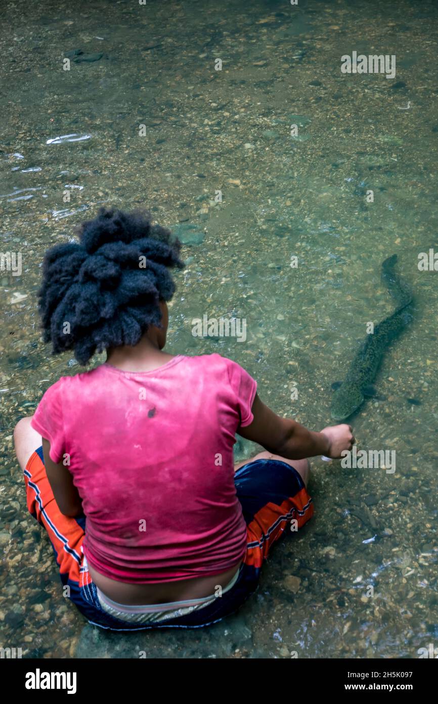 Femme qui nourrit l'anguille sauvage de la rivière Madang, Papouasie-Nouvelle-Guinée; Madang, province de Madang, Papouasie-Nouvelle-Guinée Banque D'Images