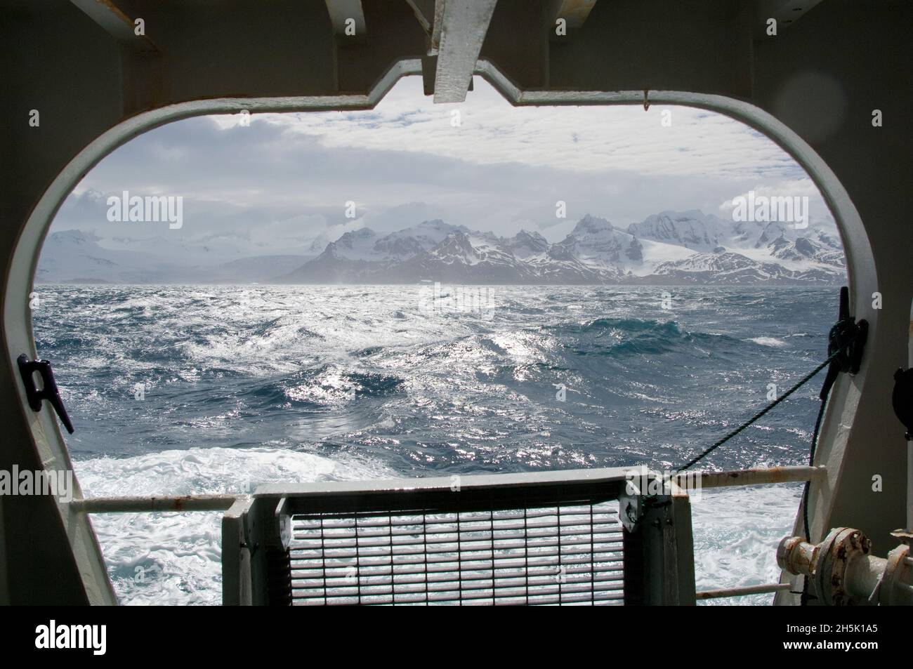 Vue prise par la fenêtre d'un navire des marais de l'océan Austral et des montagnes enneigées de l'île de Géorgie du Sud par une journée ensoleillée Banque D'Images