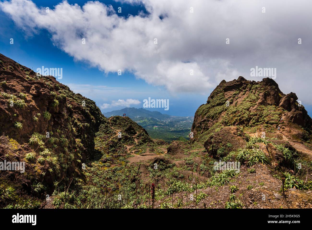 Randonneurs debout au sommet des falaises rocheuses du volcan, la Soufrière surplombant la campagne sur la Basse-Terre ; Guadeloupe, Antilles françaises Banque D'Images