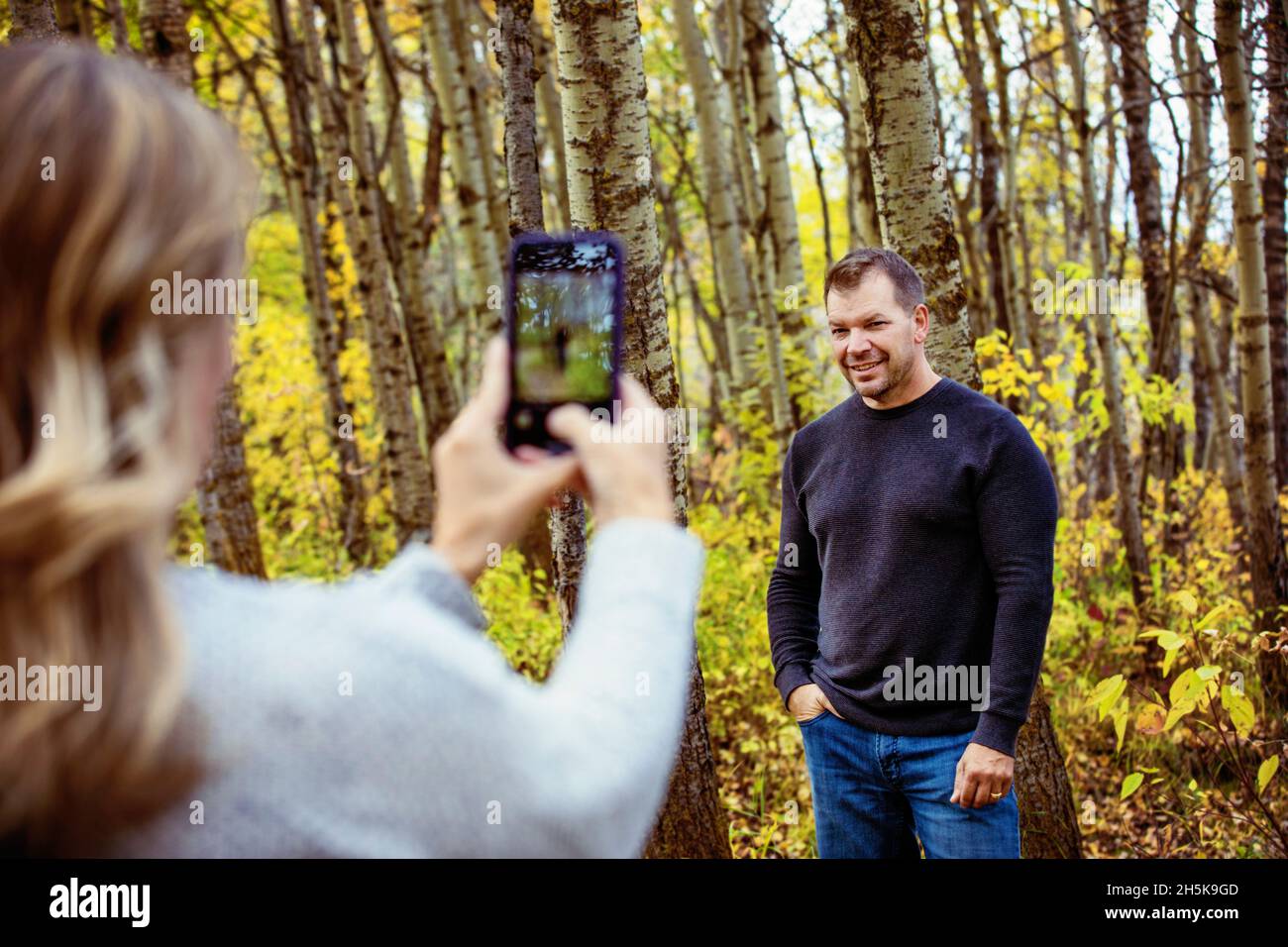 Un couple mature et marié qui passe du temps ensemble à prendre des photos les unes des autres à l'extérieur dans un parc de la ville lors d'un après-midi d'automne chaud Banque D'Images