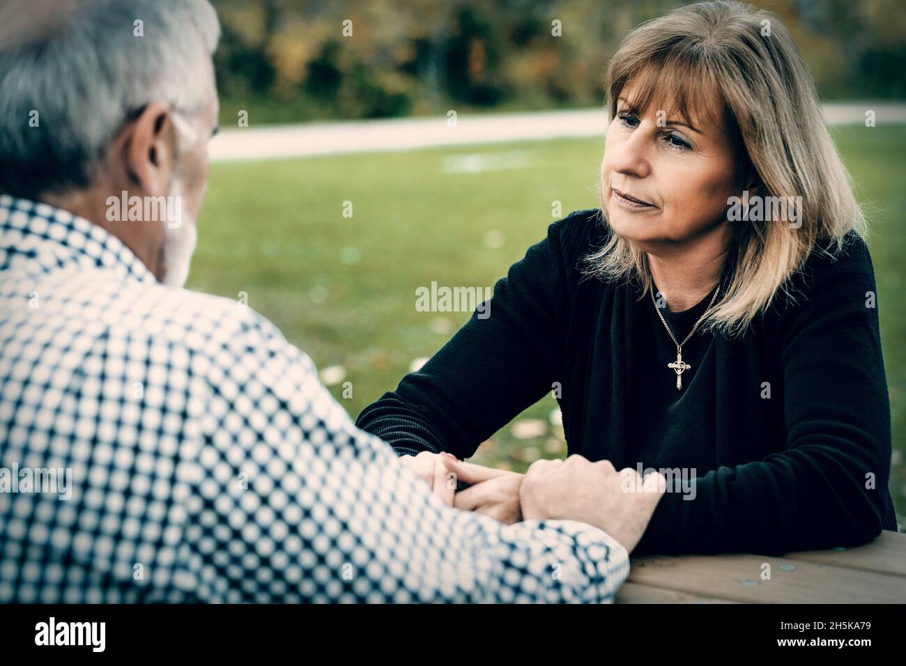 Un couple mature tenant la main à une table de pique-nique après avoir passé un certain temps de qualité à discuter de leur relation; St. Albert, Alberta, Canada Banque D'Images