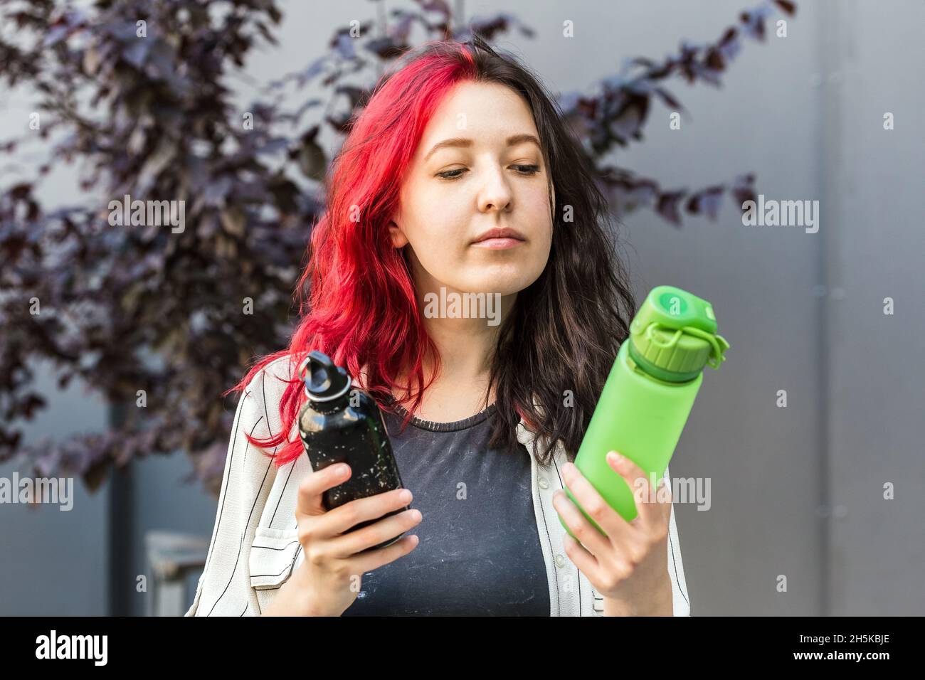 La femme choisit entre deux types de bouteilles d'eau réutilisables.Bouteille d'eau en aluminium et en silicone pour une consommation quotidienne.Style de vie durable Banque D'Images