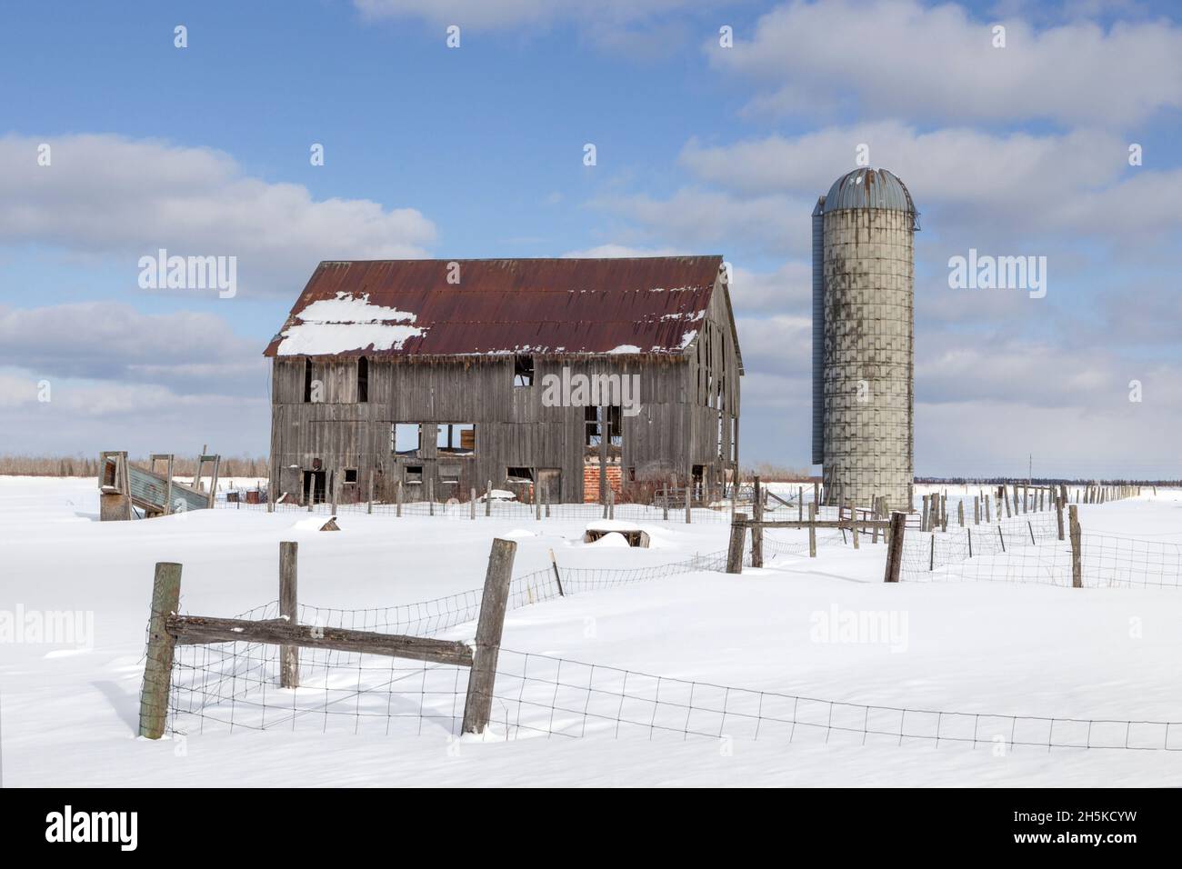 Grange en ruine avec ciel bleu et clôtures; Rudyard, Michigan, États-Unis d'Amérique Banque D'Images