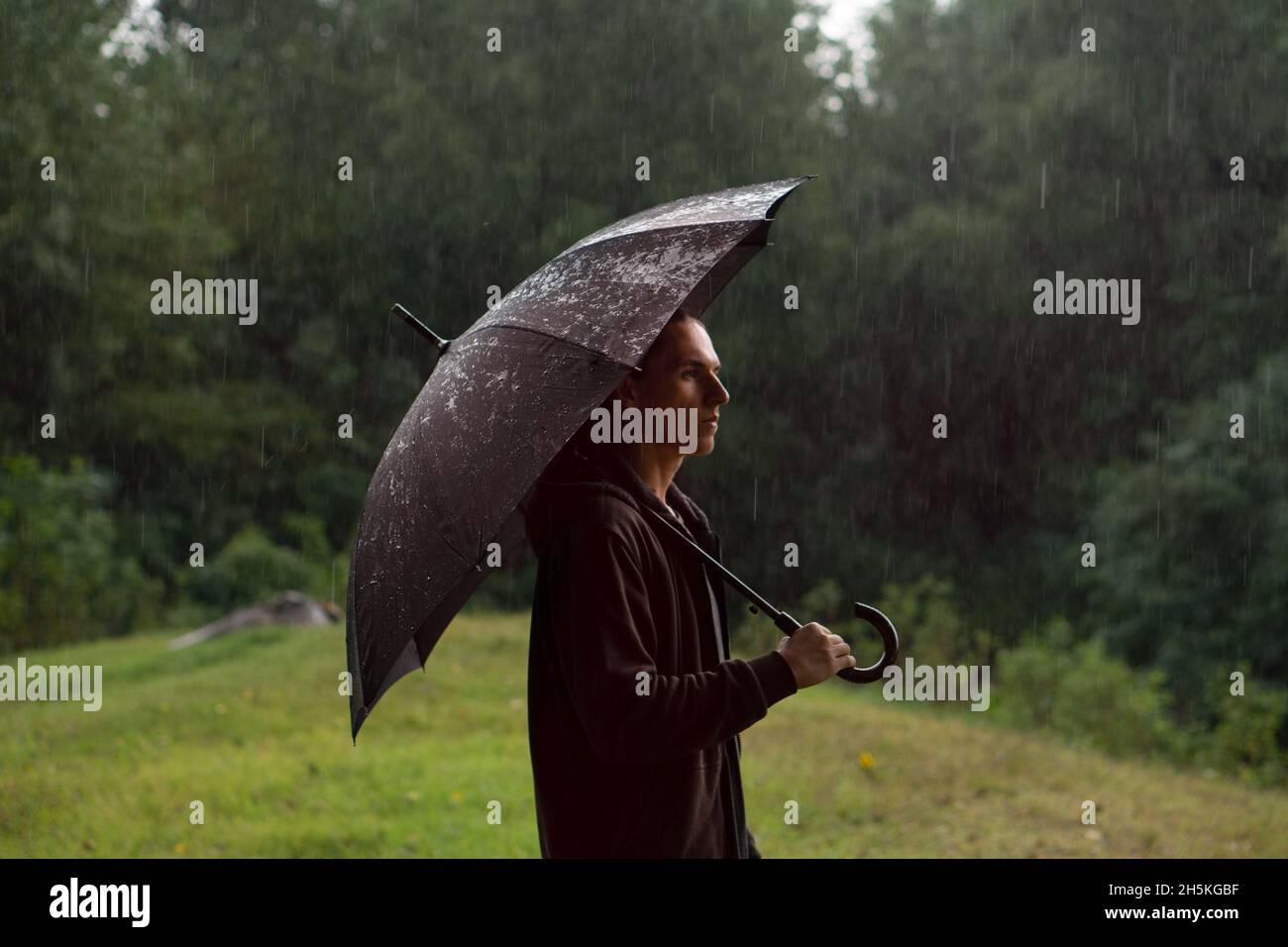 Homme dans la pluie dans le parc d'été vert Banque D'Images