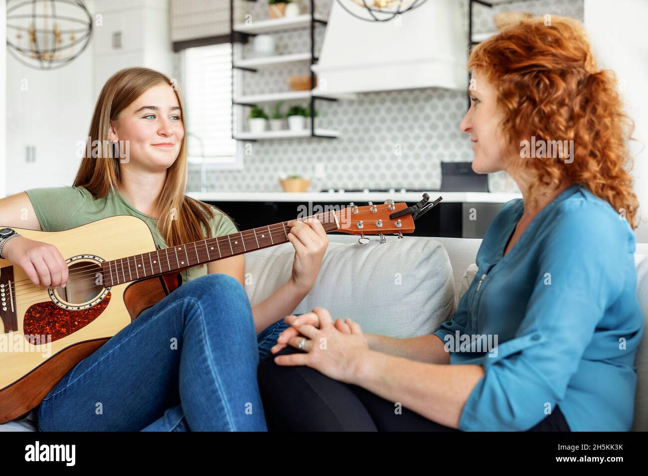 La mère et l'adolescente passent du temps de qualité ensemble à la maison tandis que la fille joue de la guitare; Edmonton, Alberta, Canada Banque D'Images