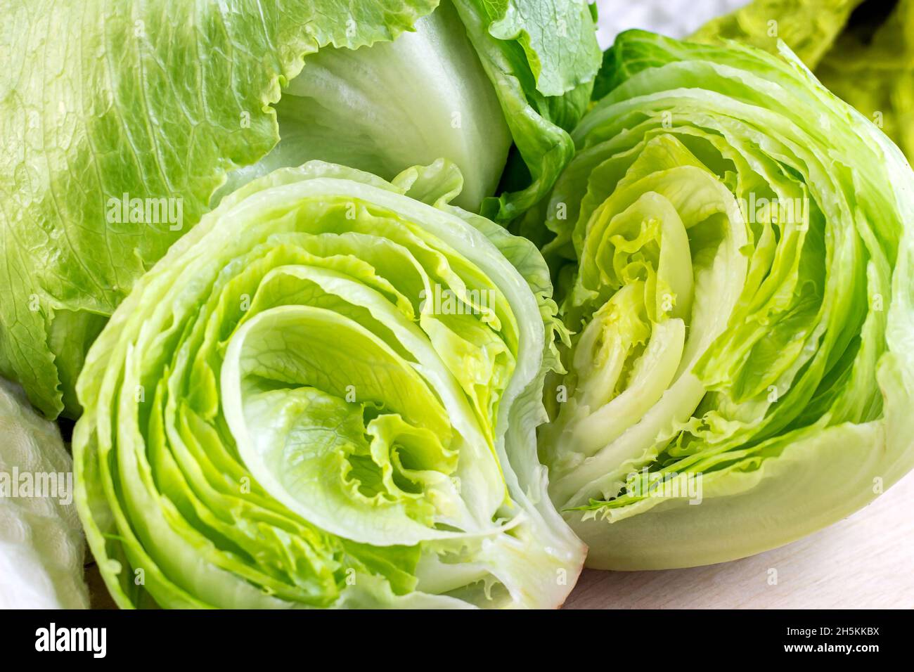 Feuilles de salade de laitue iceberg vert frais coupées sur fond clair sur la table dans la cuisine. Banque D'Images