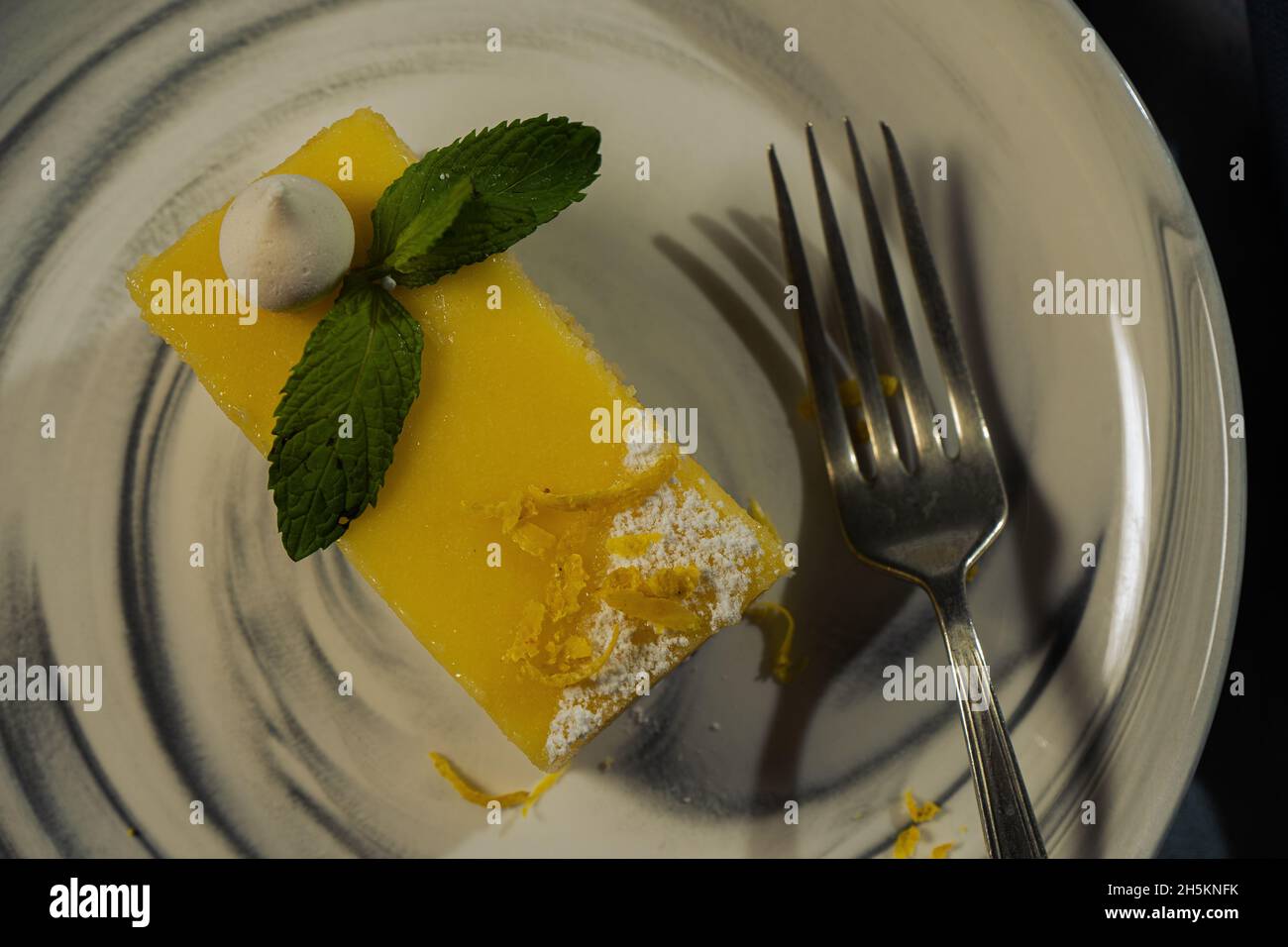 Une portion de gâteau au citron maison en forme de lingot ou de brique décorée de meringue et de feuilles de menthe.Vue de dessus.Copier l'espace. Banque D'Images