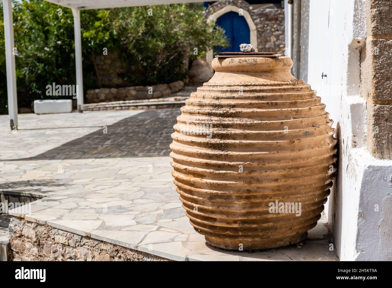 Ancienne amphore en céramique faite à la main avec couvercle dans un jardin, contenant traditionnel d'artisanat en argile.Décoration extérieure de maison d'île grecque, village de Chora en Grèce. Banque D'Images