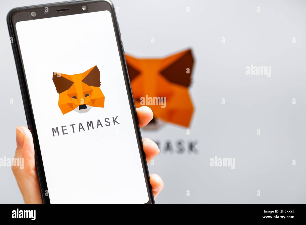 Ukraine, Odessa - octobre, 9 2021: Main tenant mobile avec l'application MetaMask fonctionnant à l'écran de smartphone avec le logo MetaMask en arrière-plan.MetaMask l'est Banque D'Images
