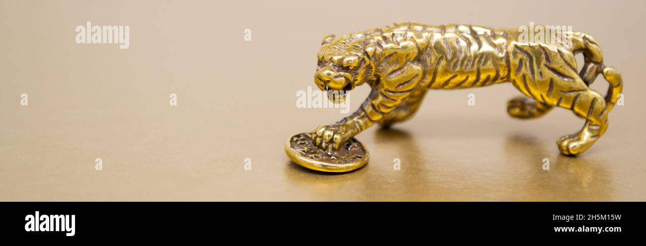 Bannière avec la figure en bronze d'un tigre avec une pièce de monnaie - le symbole de la nouvelle année chinoise 2022 sur un fond doré, espace de copie.Bonne chance, fi Banque D'Images
