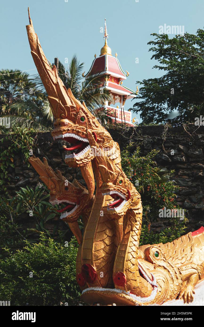 Photo verticale d'un dragon d'or à trois têtes près d'un temple Banque D'Images