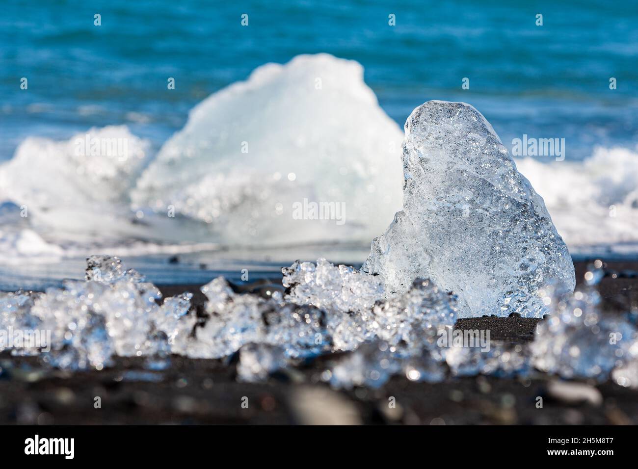 Changement climatique concept de réchauffement climatique, gros plan de la fonte de glace sur une plage de sable noir volcanique en Islande, un iceberg dans les vagues peut être vu dans le b Banque D'Images