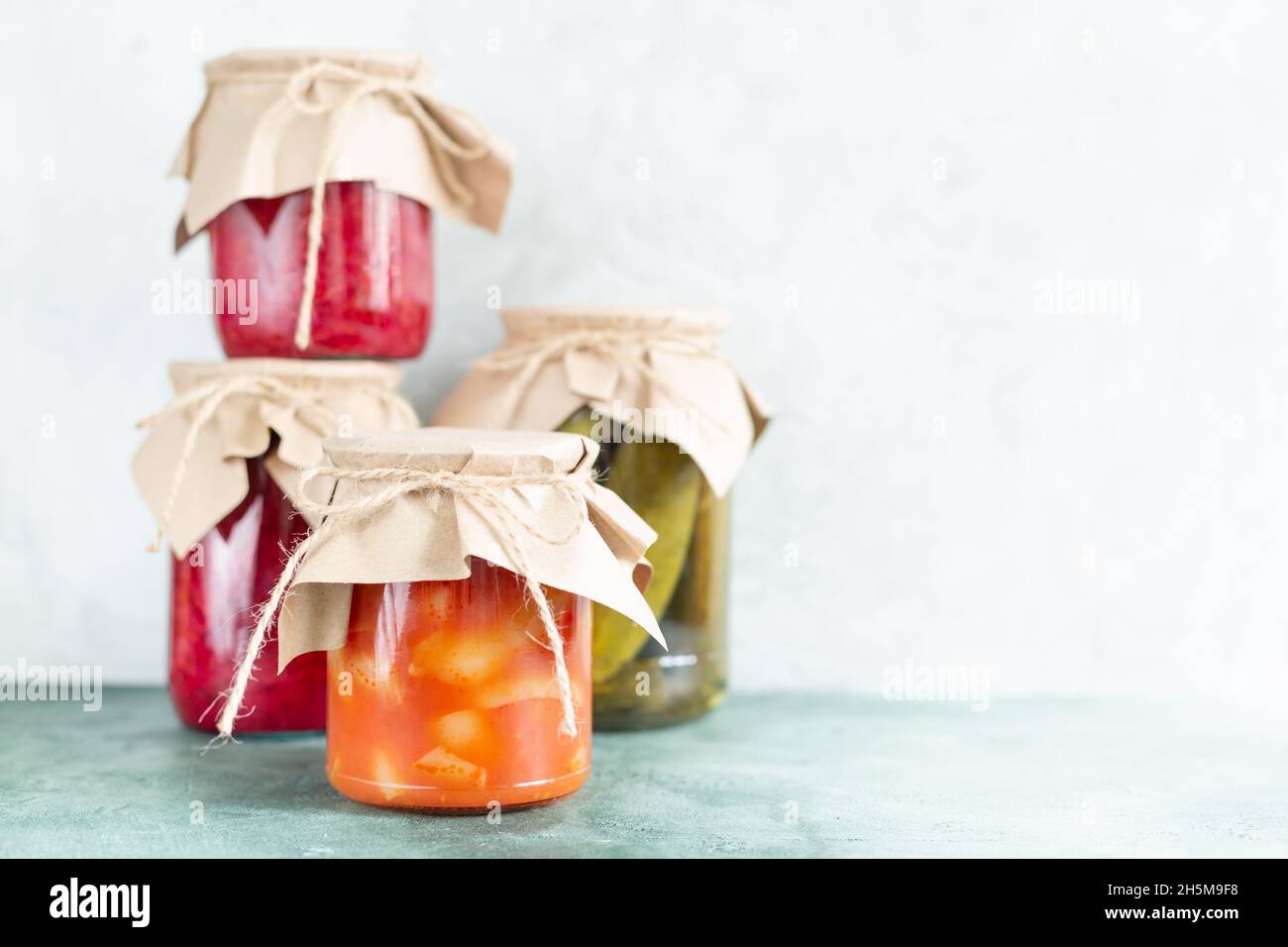 Cornichons, légumes conservés dans des pots en verre sur fond vert clair avec espace de copie.Préparations faites maison, stockage des aliments.Aliments écologiques emballés dans Banque D'Images