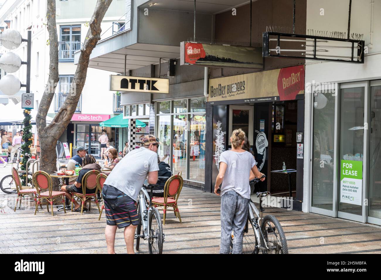 Cyclistes adultes et leurs vélos dans le centre-ville de Manly Beach, scène urbaine, Sydney, Australie Banque D'Images