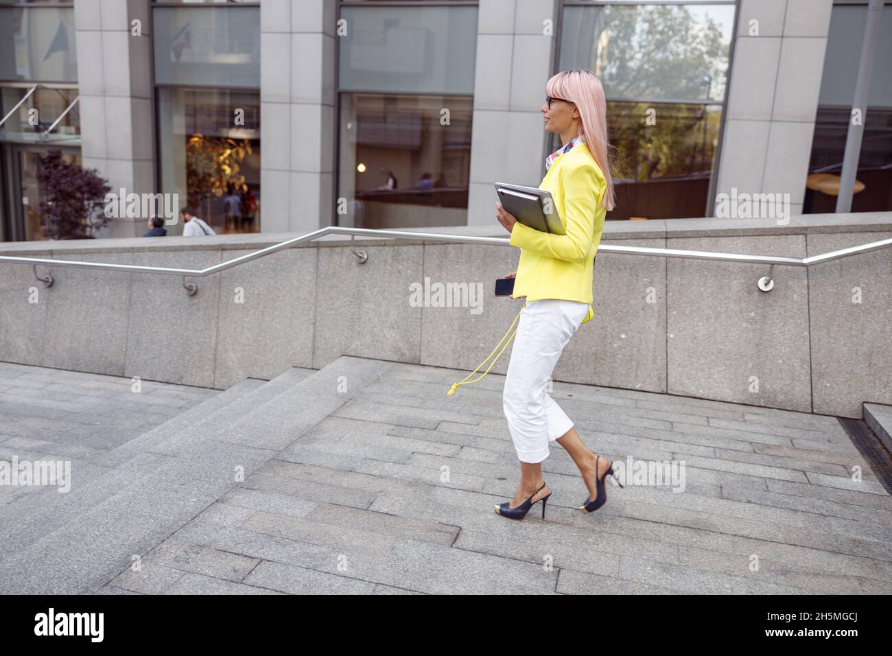 Femme dans un blazer jaune en descendant les escaliers de la rue Banque D'Images