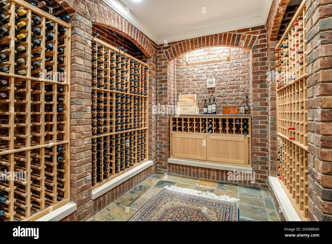 Une grande cave à vin dans une maison de luxe avec des murs en briques et des casiers à vin en bois. Banque D'Images