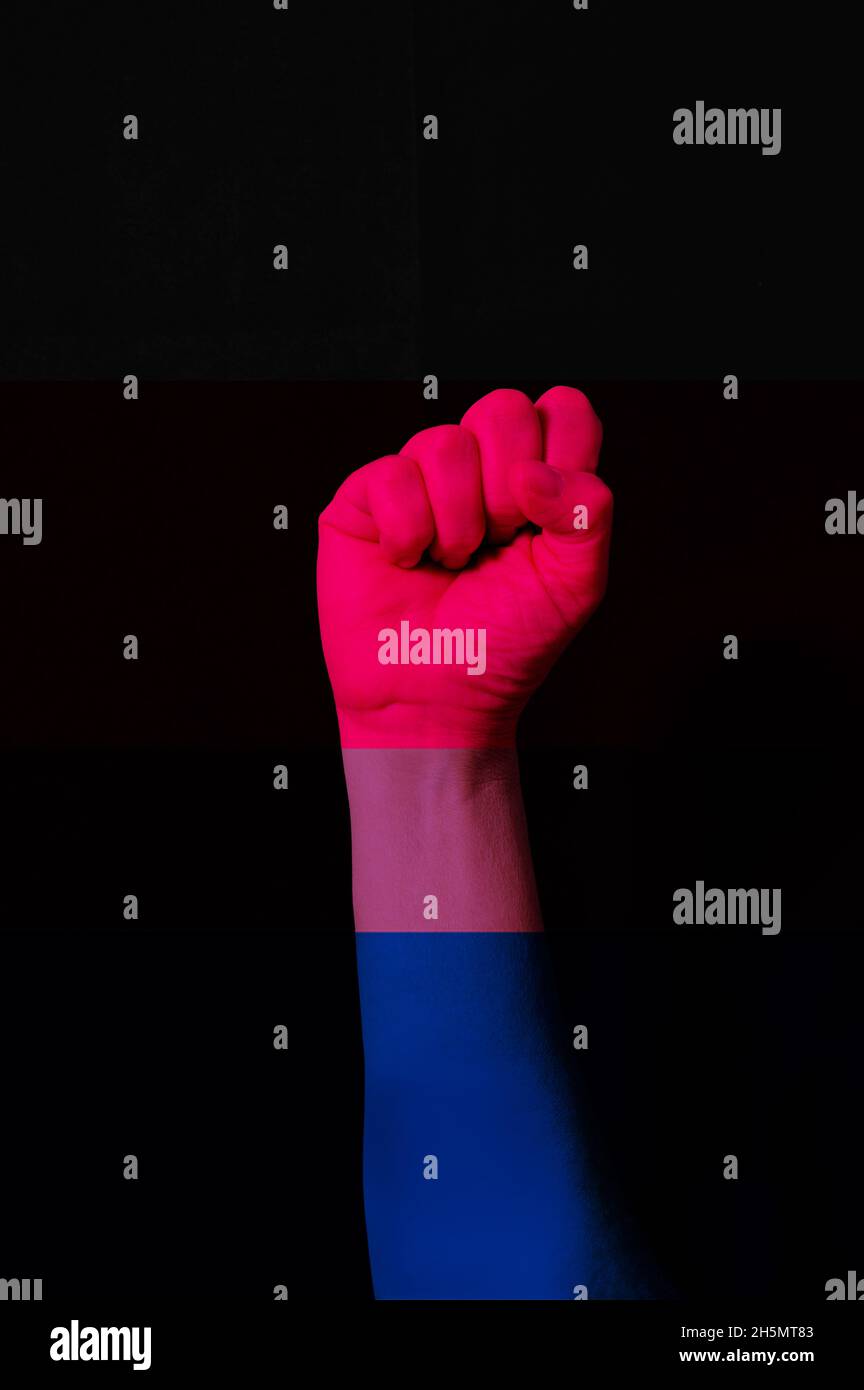 Main de poing avec drapeau de fierté bisexuel à motif isolat sur noir.Concept de droits LGBTQ+ Banque D'Images